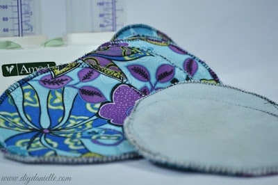 How to sew your own nursing pads without a serger. This is an easy sewing machine project to make a reusable product that will save you money. Pictured: Blue floral DIY nursing pads with breast pump in the background.