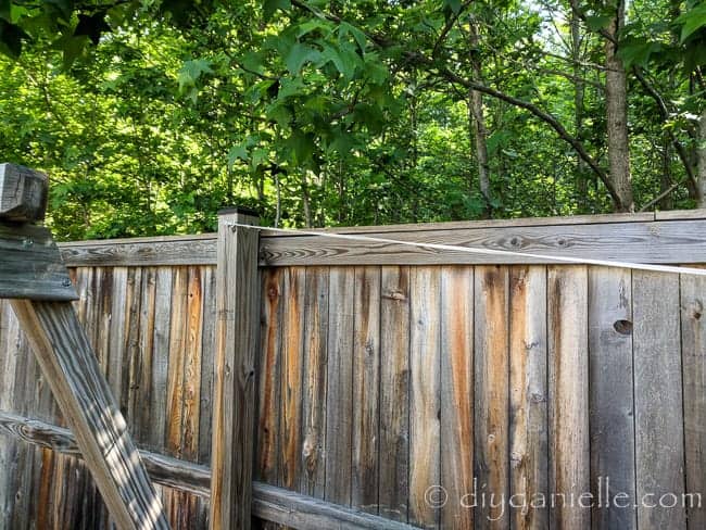 Shade sail attached to the wood fence over a sandbox to provide shade for kids playing.