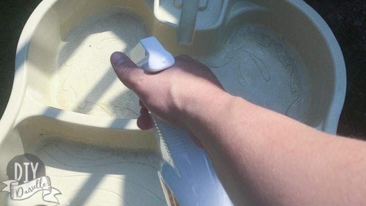 Using homemade cleaning spray on a water table.