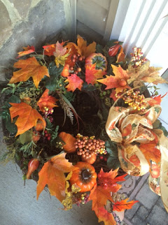 Using a wreath to decorate an empty planter to make Fall porch decor.