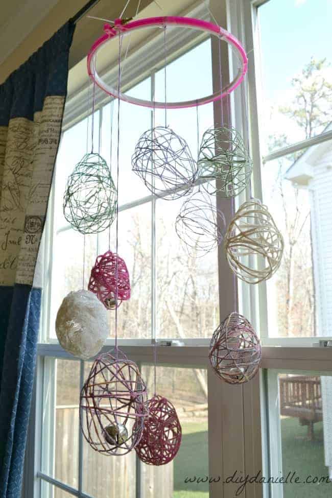 Our Easter Egg Wind Chime DIY, hanging from a curtain rod.