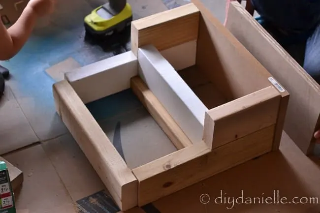 Screw wood pieces together to shape DIY stepping stool.