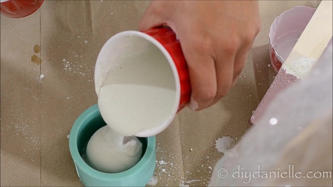 White concrete into a silicone mold for a DIY candle holder.