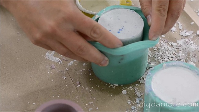 Removing hardened concrete from a silicone candle holder mold.