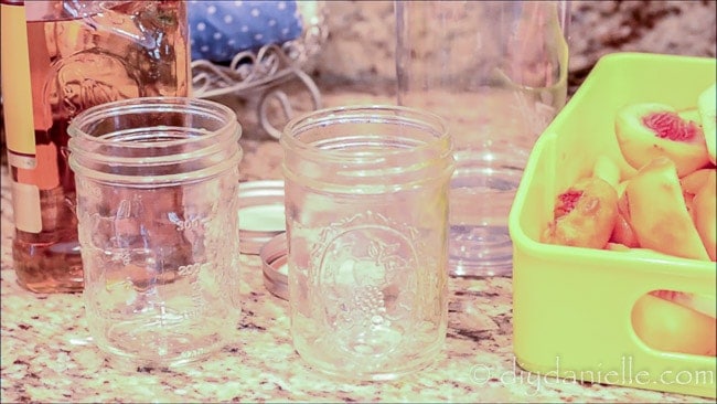 Supplies for making fruit flavored liquors: peaches, mason jars, vodka or tequila.