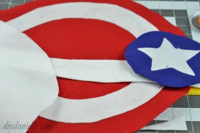 Sew on embellishments to the shield. These are the circles and star from the Captain America shield.