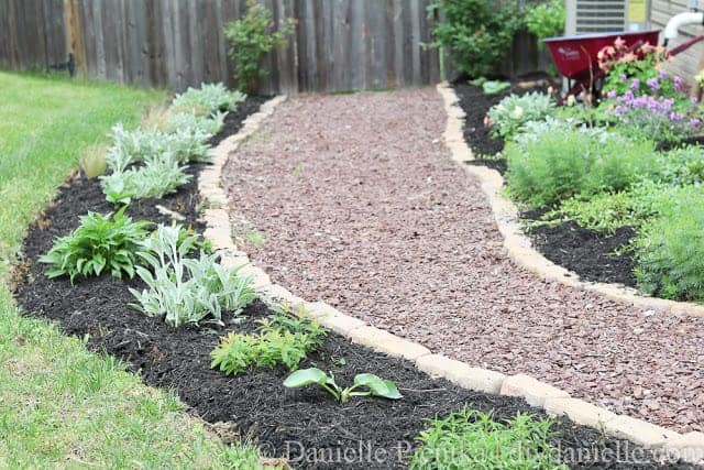 Garden path with red stone and bricks lining it.