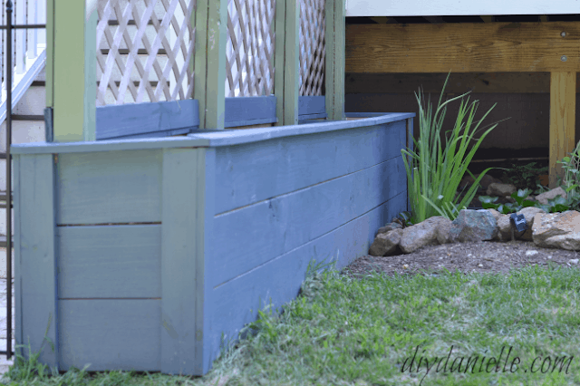 DIY Planter Box: Blue planter with green trellis beams. Vinyl trellis. Pond to the side of the planters.