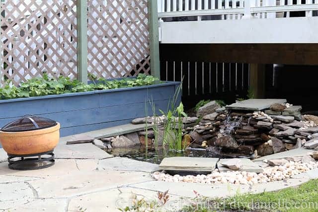 Landscaping with privacy planters, a pond, and patio. 