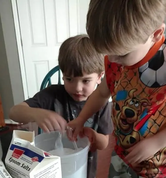 Kids helping make gifts for their teachers, mason jars full of orange mint bath salts.