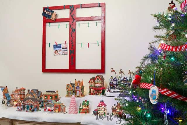 Holiday card display hanging up by the tree and Christmas village.