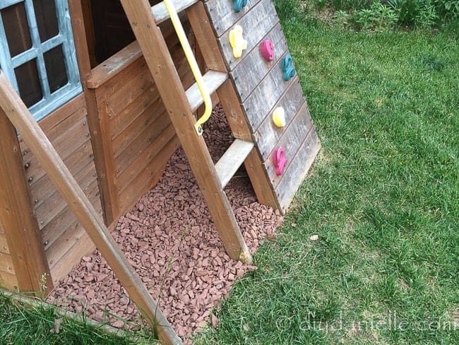 Red barn rock around a swingset to prevent weeds.