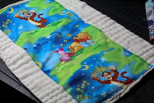 Cotton fabric embellishing a prefold so it can be used as a burp cloth.