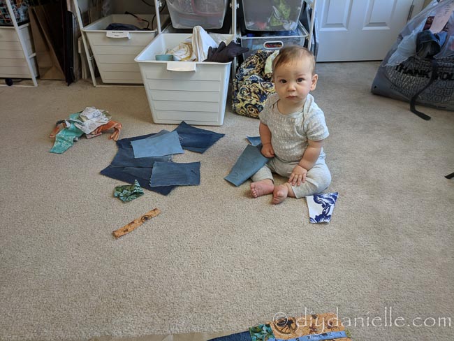 Cutting up scrap fabric for a patchwork bag. Baby helping.