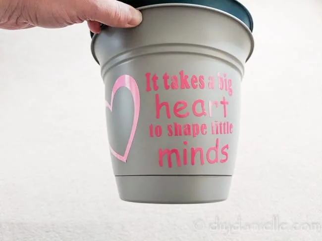Pot with a vinyl design that says "It takes a big heart to shape little minds."