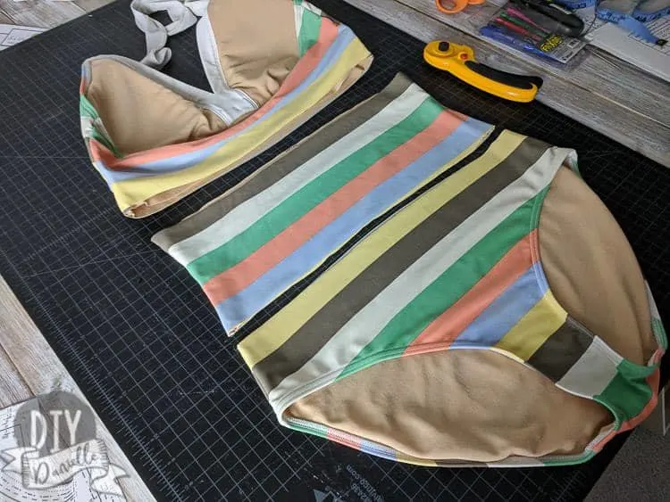 Cutting apart a one piece swim suit to remove the middle of the torso section.