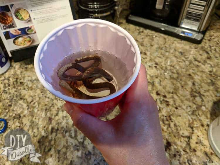 Soaking rusted S hooks in vinegar and water to clean off the rust.