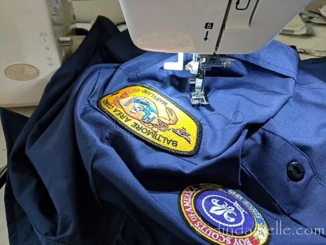 Using a sewing machine to sew on Boy Scout patches with a zig zag stitch.