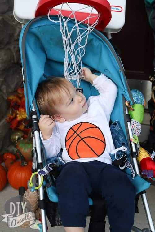Baby as a basketball in a stroller that has a basketball hoop attached. Swoosh!