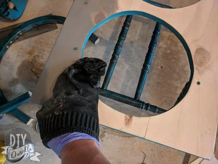 Weather gray stain being applied to the top of a raised dog bowl holder.