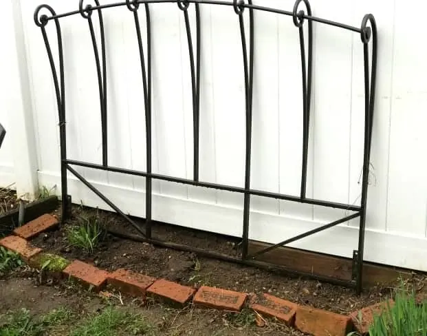 Headboard used as a trellis in a garden bed.