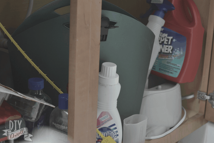 Disorganized bathroom cabinet with lots of junk under it.