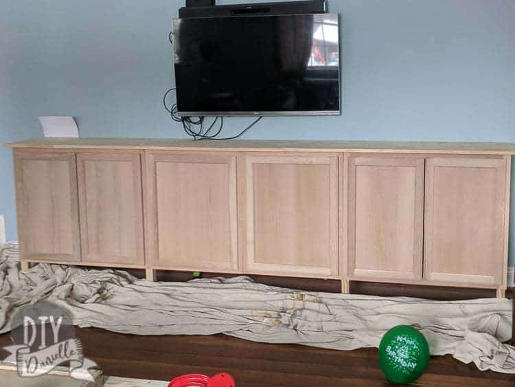 Unfinished wood cabinets installed as entertainment center storage. They'll be finished with stain, then dry brushed.