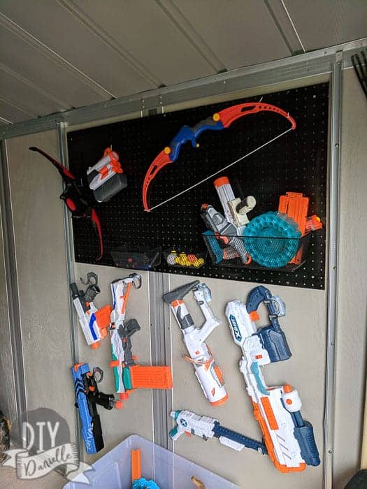 Nerf gun storage in the kids garage. Super organized with cheap $1 hooks, pegboard, and small containers.