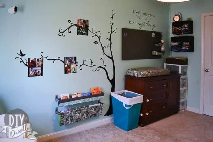 Large wall decal with a tree. Pegboard for nursery storage above the changing table. Cloth diaper storage on the wall. Book slings.