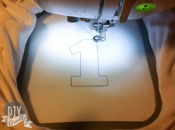 Embroidering a 1 onto a shirt.