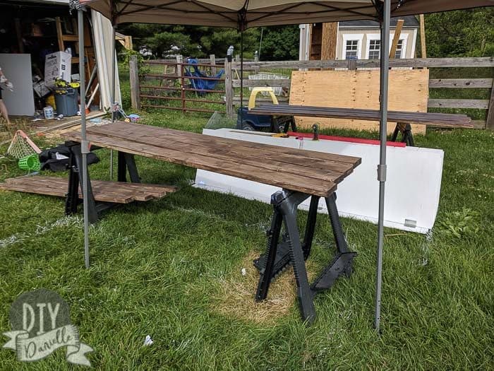 Staining wood under a canopy for shade.