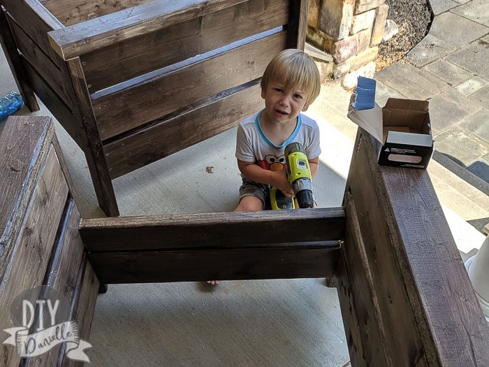 Toddler "helping" build the chairs... not happy because he doesn't have the necessary agility to do it.