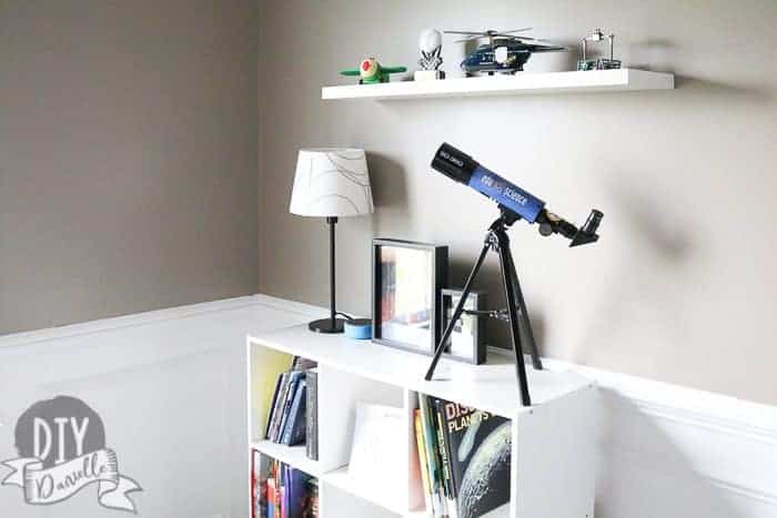 White bookshelf against a white chair rail with white underneath and gray walls above.