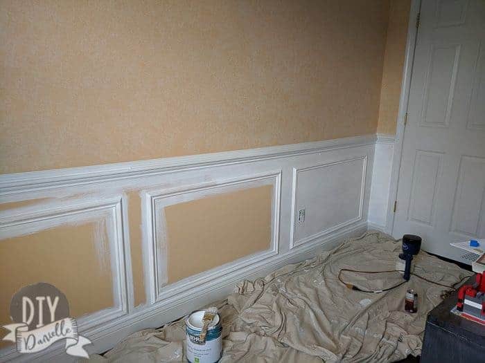 Spray painting under the chair rail to be white, matching the chair rail and baseboard. I used a paint brush to paint around the trim before spraying. 