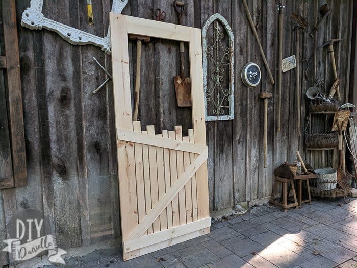 Unfinished wood screen door DIY in front of my friend's junk wall.