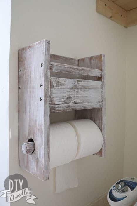 Rustic toilet paper holder that has room for two rolls, plus has storage above it for a magazine or family cloth. 