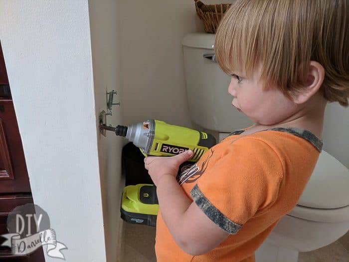 My son helping remove the brackets for the old toilet paper holder.