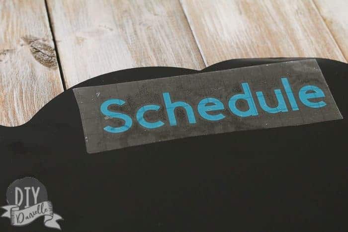 Applying the word "schedule" to the top of my chalkboard using Cricut transfer paper.