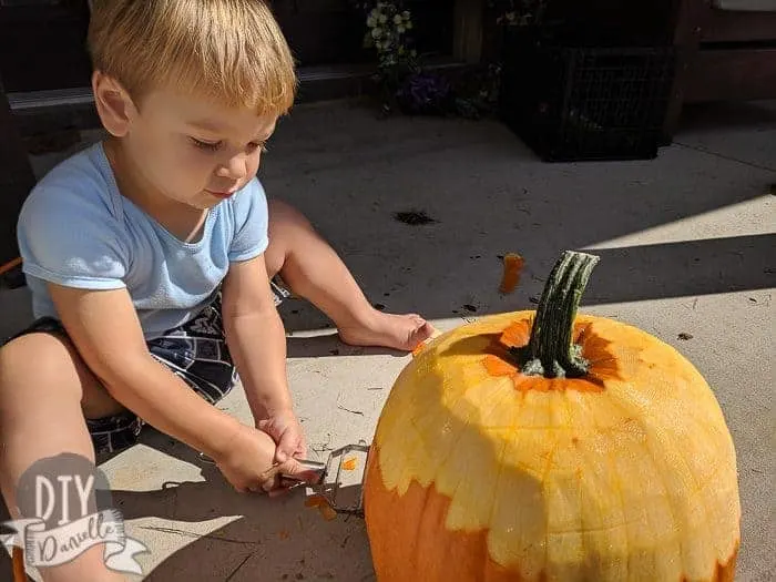 Toddler peeling the pumpkin.