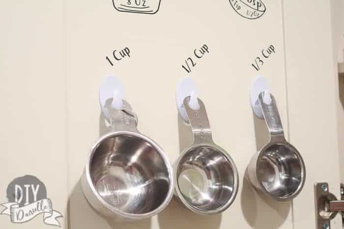 Pictures of the cups hanging on cheap hooks inside the cabinet, carefully labeled with my Cricut.