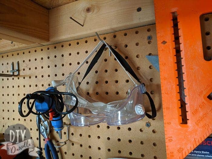 Safety glasses hanging on pegboard of the work bench.