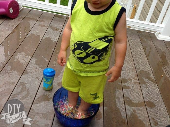 Son standing in a bowl of water beads.