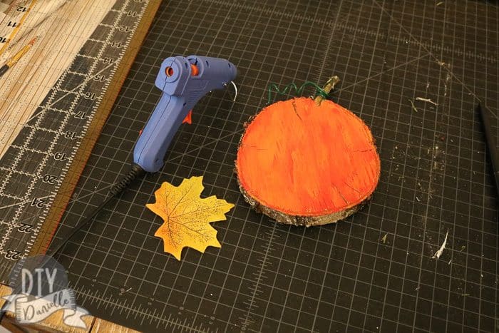 Using my glue gun to add a leaf to the pumpkin wood slice.