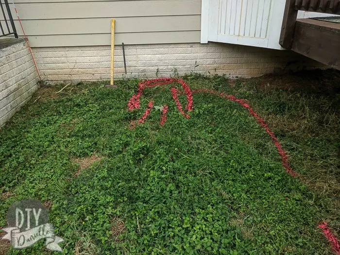 Red spray paint on grass marking where the wire and charging station will go. 