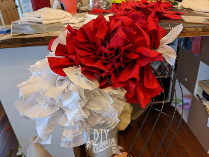 Progress photo of adding red and white stripes to a candy cane wreath form. 