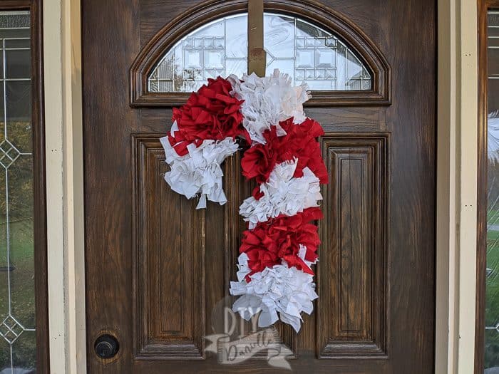 Red and white candy cane wreath. Super full wreath against a dark door. 