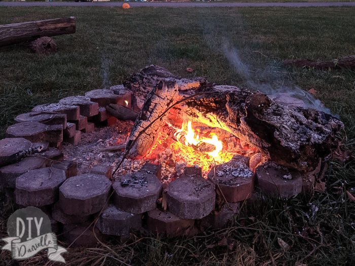 Fire pit made with pavers... with fire inside it and logs.