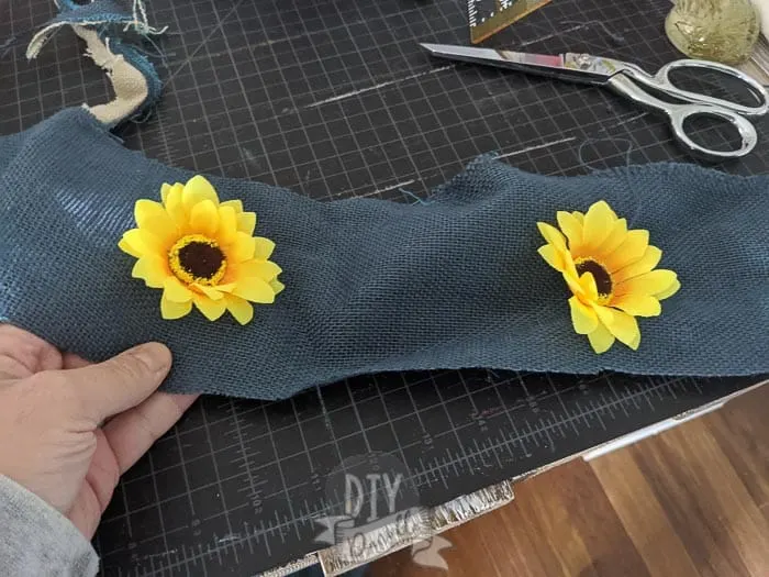 Yellow sunflowers contrasting against blue burlap cut into strips. 