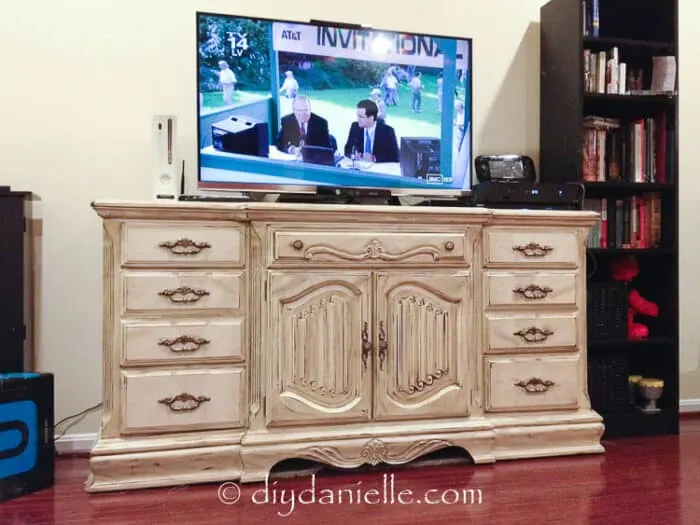 Rustic white distressed tv stand made from a bureau. TV on top.