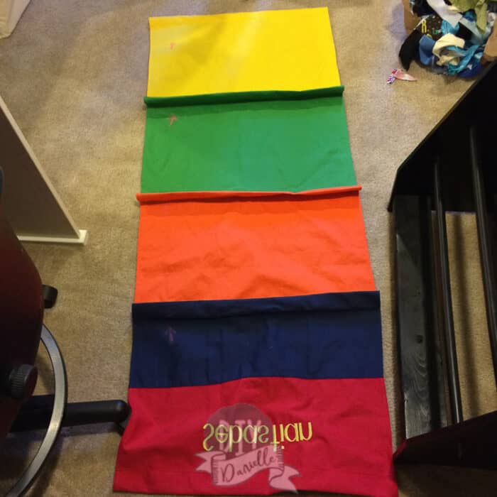 Old slings laid out as a template for the new ones. These were rainbow colored and said Sebastian.